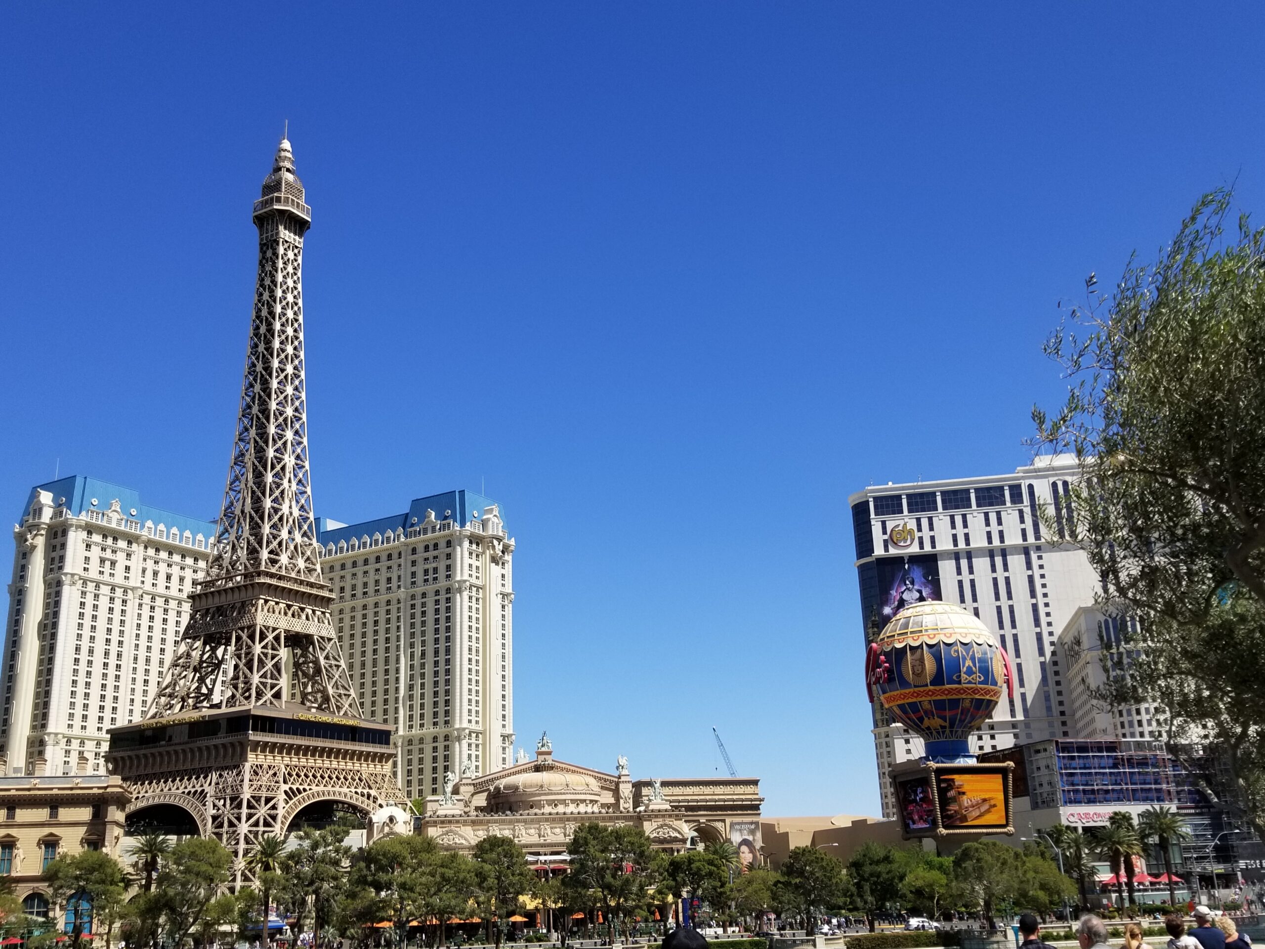 This image shows the Las Vegas skyline on a cloudless sunny day and features the Eiffel Tower replica at Paris, a replica hot air balloon, and several other hotel casinos.