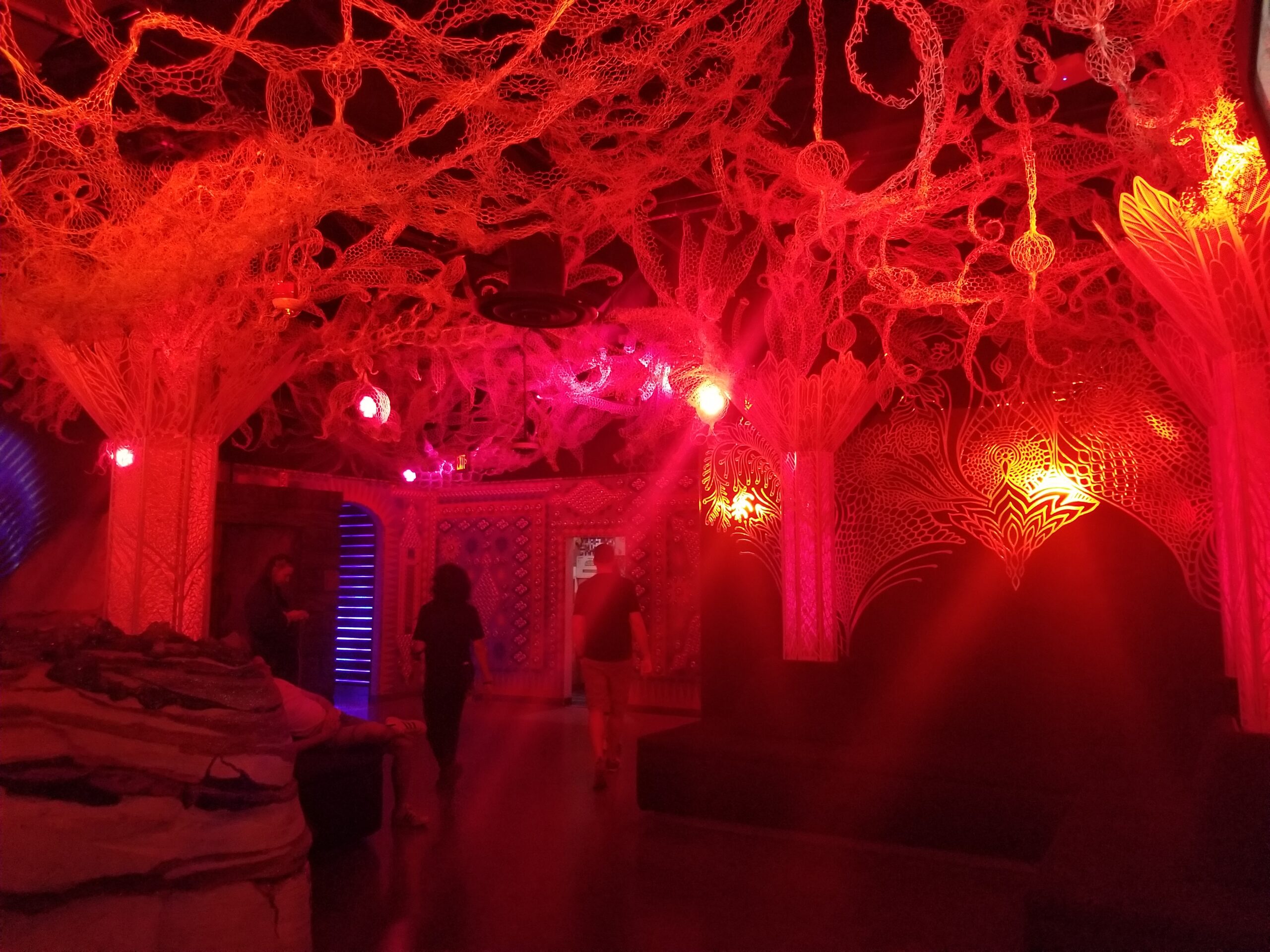 Inside the Omega Mart attraction at AREA15 in Las Vegas. This section of the exhibit features an area bathed in red light with trees that have hanging pieces similar to a willow.